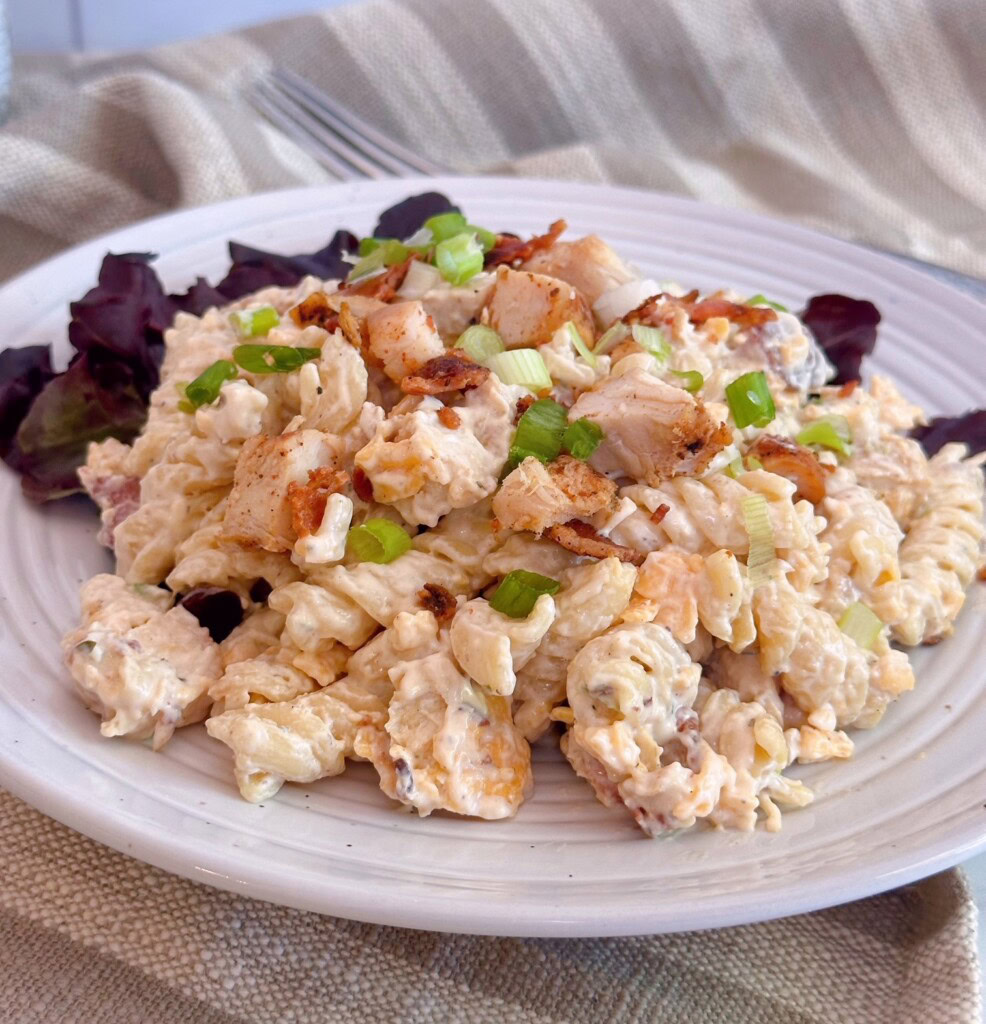 Chicken Bacon Ranch Pasta Salad serving on a plate with red leaf lettuce.