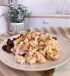 Serving of Chicken Bacon Ranch Pasta Salad on a rustic plate with red leaf lettuce.