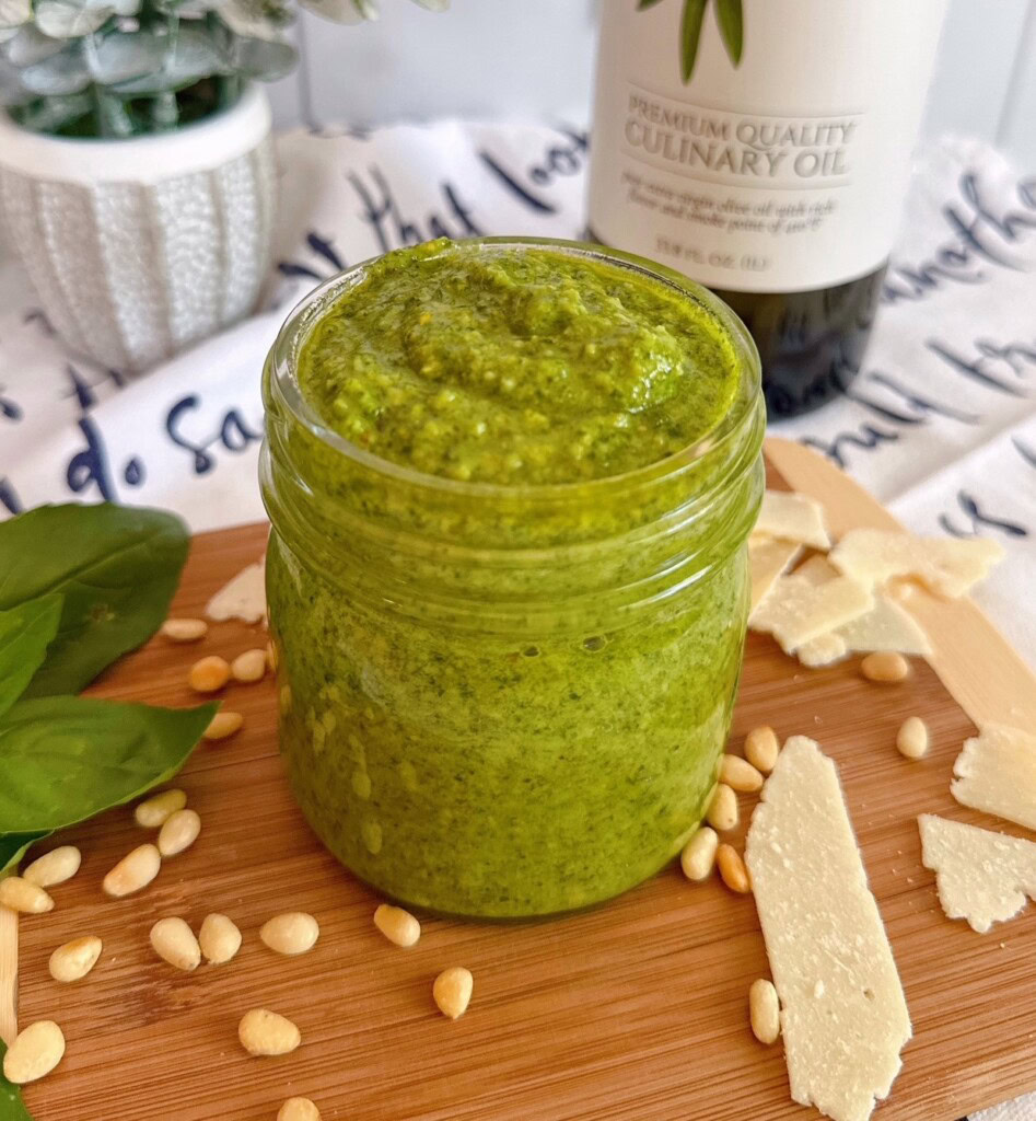 Pesto sauce in a jar on a small wooden cutting board. 