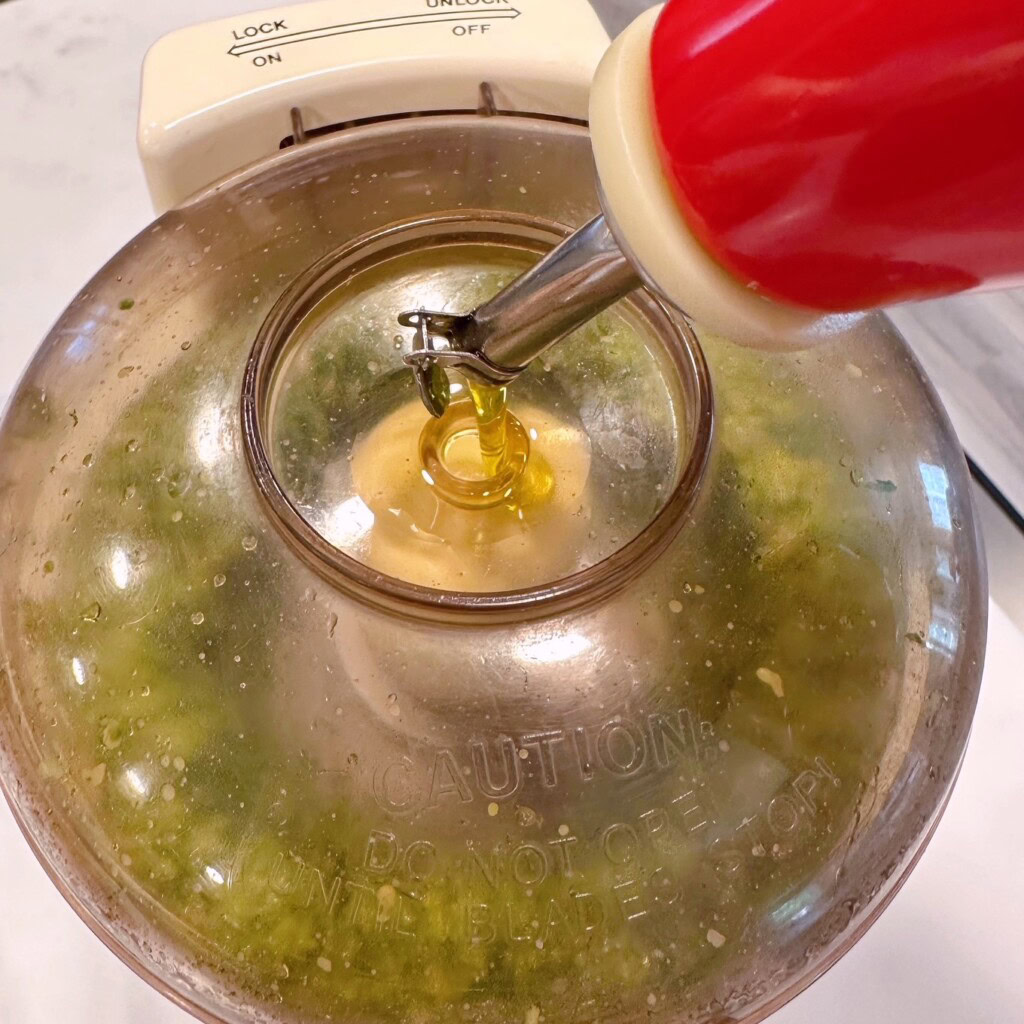Adding extra Olive Oil while processing pesto sauce.