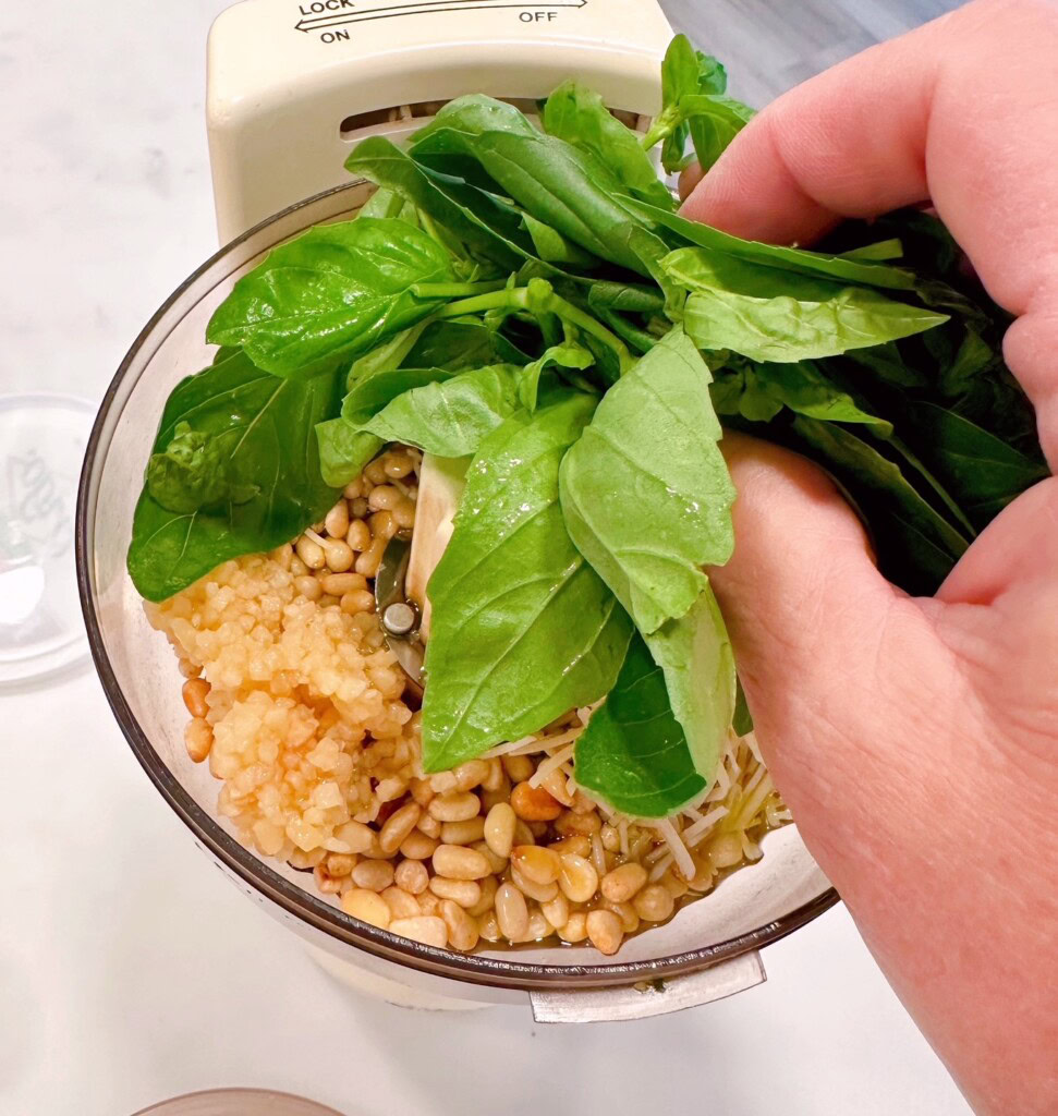 Adding basil to the food processor.