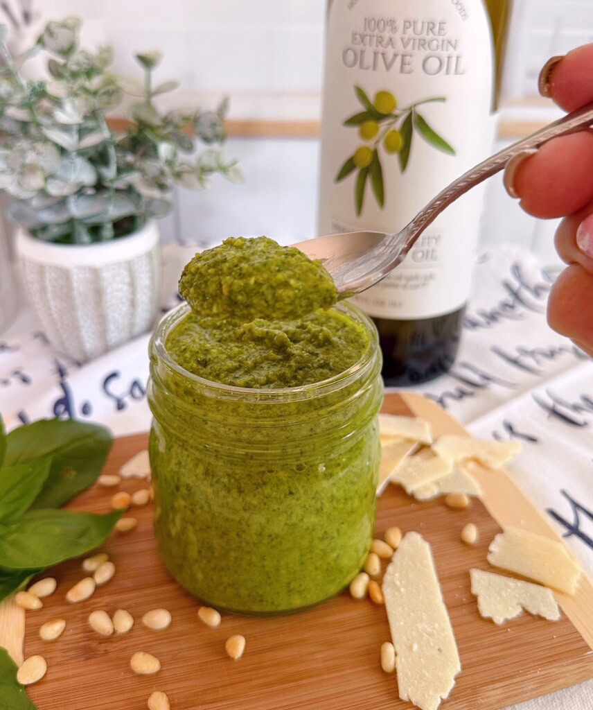 Spoonful of fresh pesto sauce coming out of the jar.