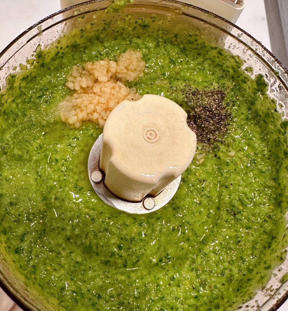 Adding additional garlic and pepper to pesto sauce. 