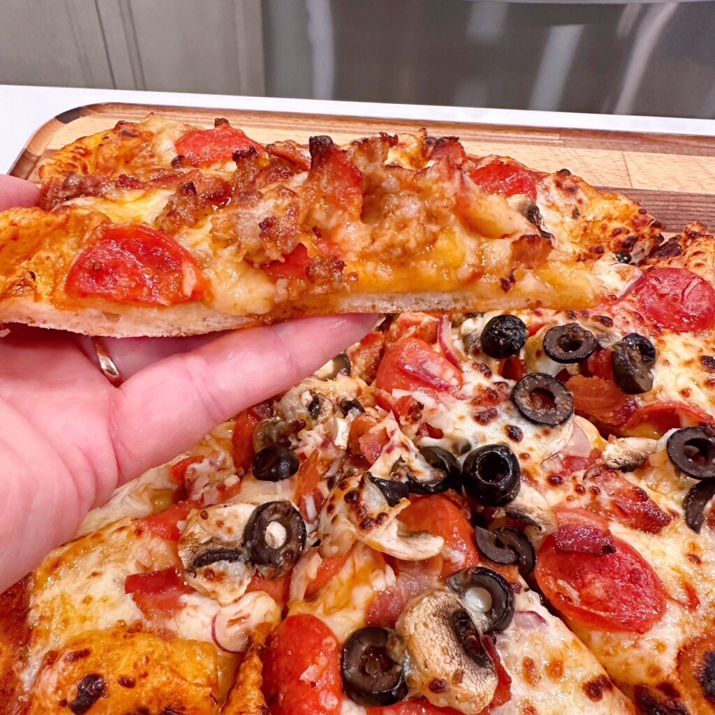 Holding a slice of pizza on homemade pizza crust.
