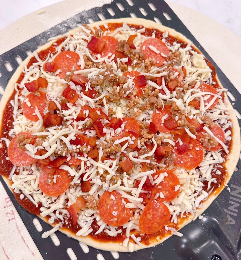 Adding toppings to pizza dough.