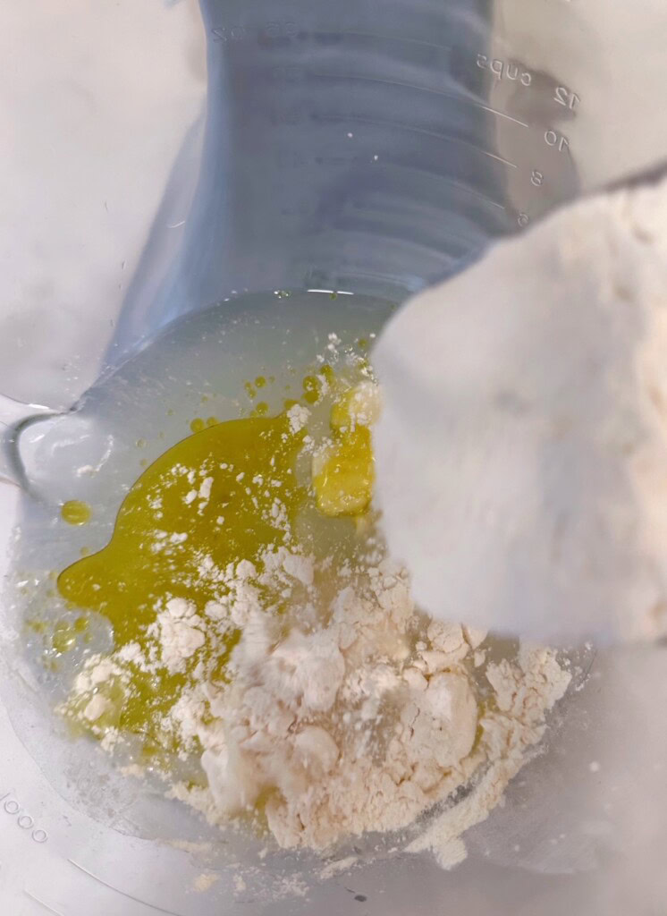 Adding flour to water mixture in mixing bowl.