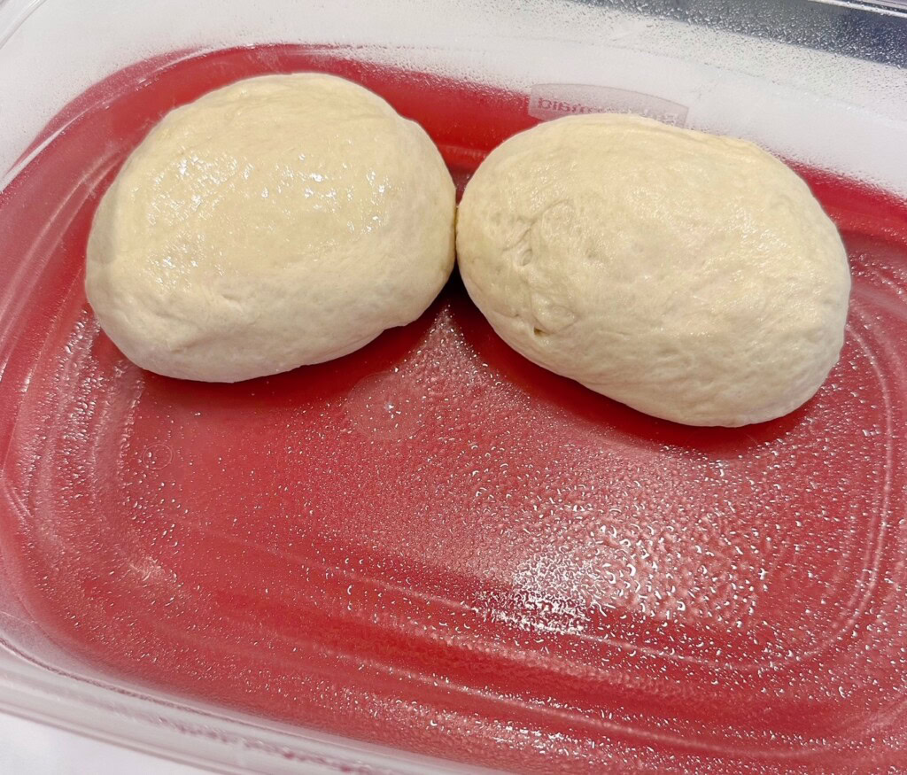 Placing dough balls into a prepared food container.