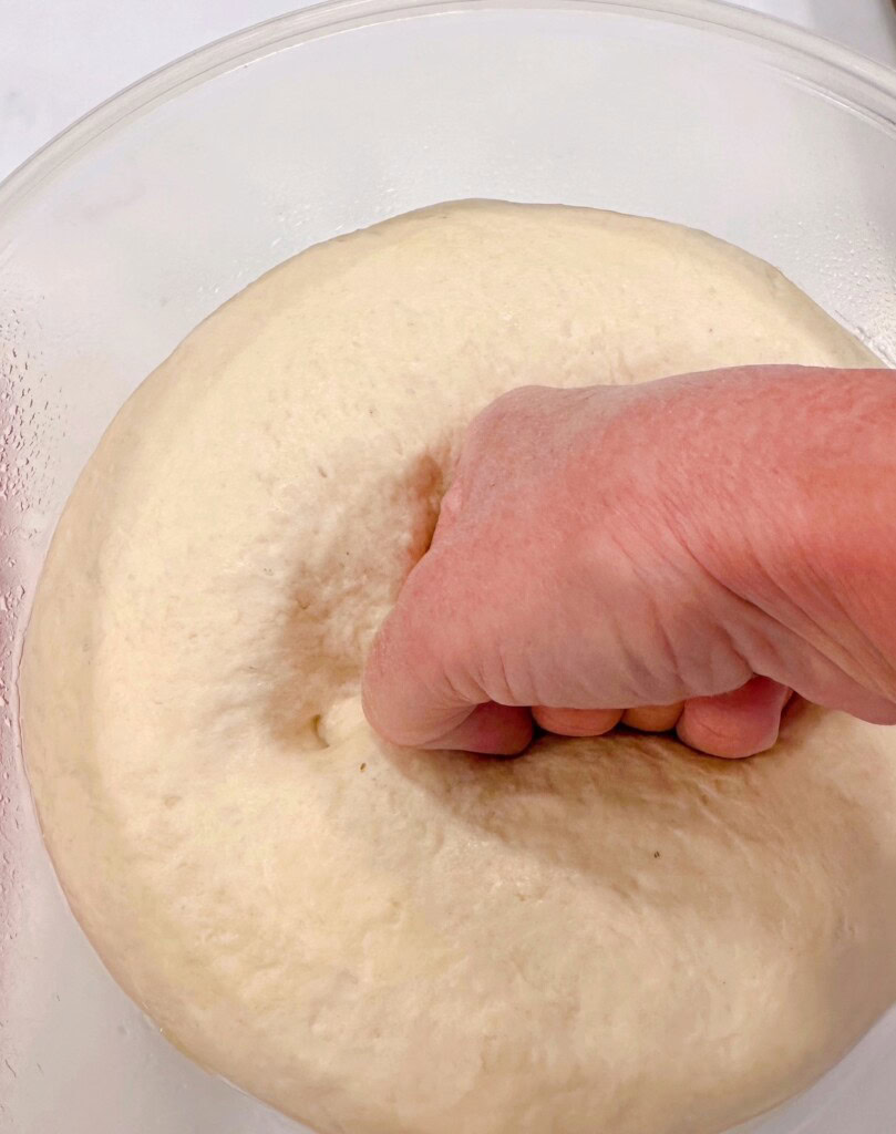 Punching down risen pizza dough.