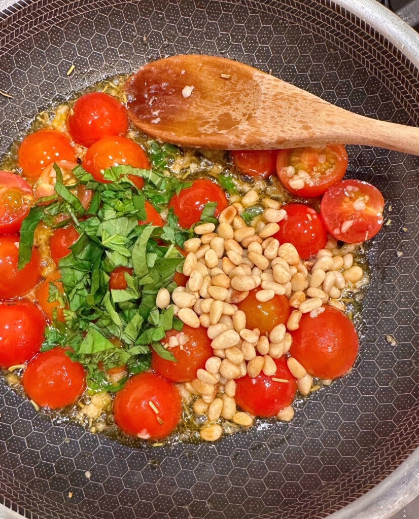 Add the fresh basil and pine nuts to the skillet with the tomatoes.