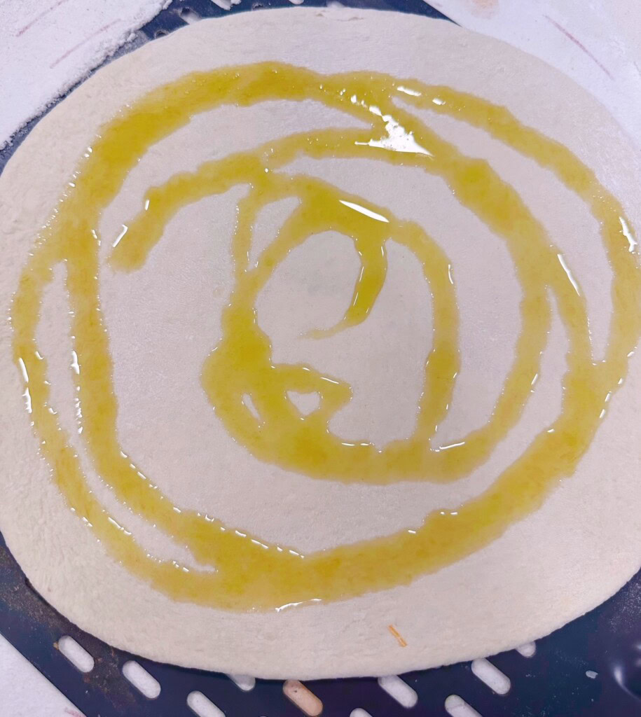 Pizza crust drizzled with olive oil.