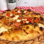Tomato Basil Pizza upclose with a woven mat underneath it.