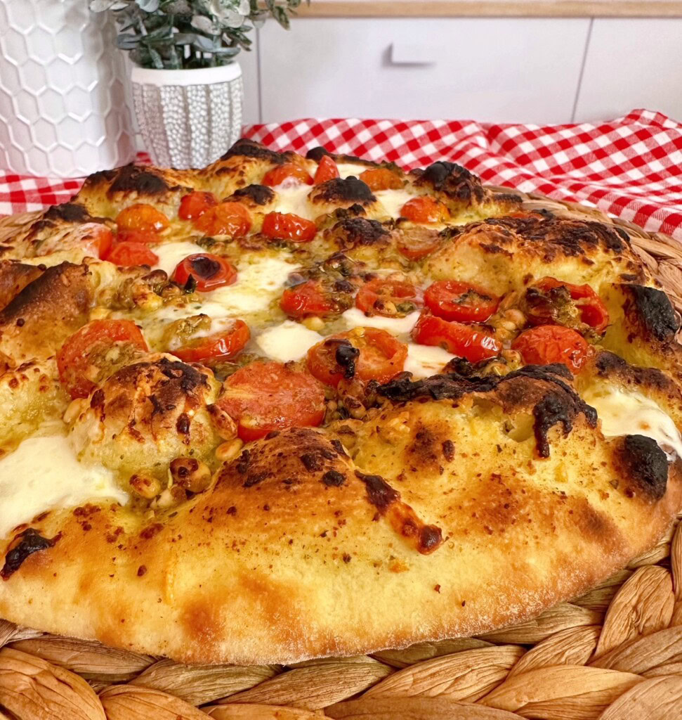 Tomato Basil Pizza upclose with a woven mat underneath it. 