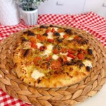 Homemade Tomato Basil Pizza on a table with a red and white checker napkin.