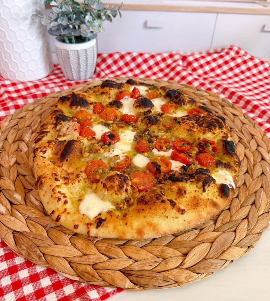 Homemade Tomato Basil Pizza on a table with a red and white checker napkin.