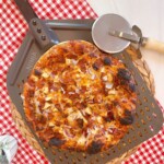 BBQ Chicken and Bacon Pizza on a pizza paddle with a pizza wheel.