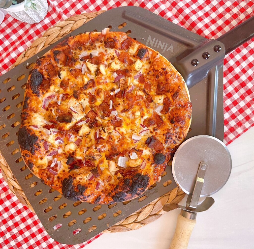 BBQ Chicken and Bacon Pizza on a pizza paddle with a pizza wheel.