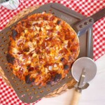 BBQ Chicken and Bacon Pizza on a pizza paddle with a pizza wheel.