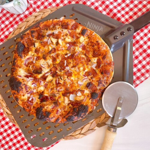 BBQ Chicken and Bacon Pizza on a pizza paddle with a pizza wheel.