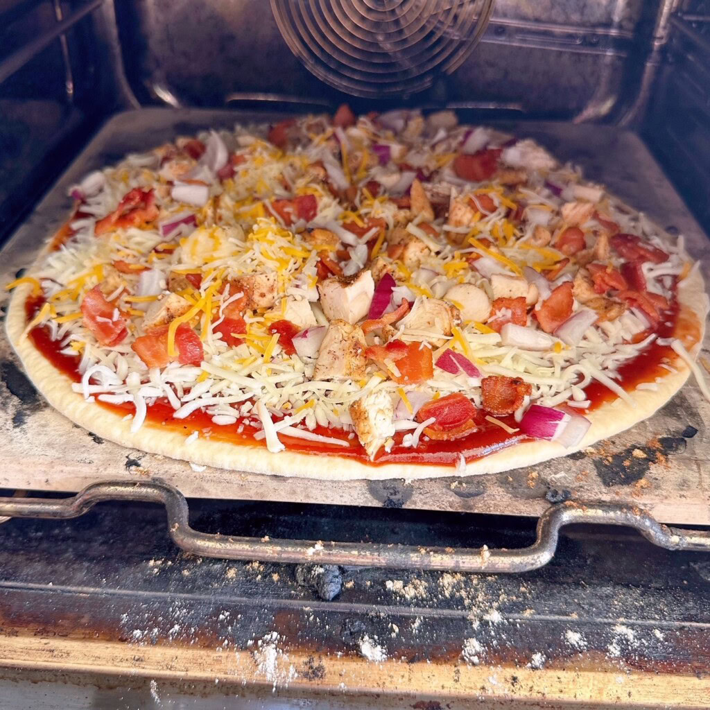 Placing the pizza in the pizza oven.