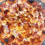 Baked pizza coming out of the oven and placed on a cutting board.