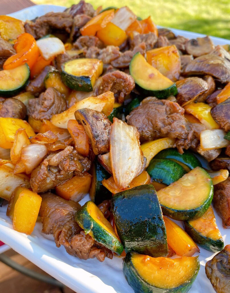 Grilled teriyaki steak and veggies upclose on a serving tray.