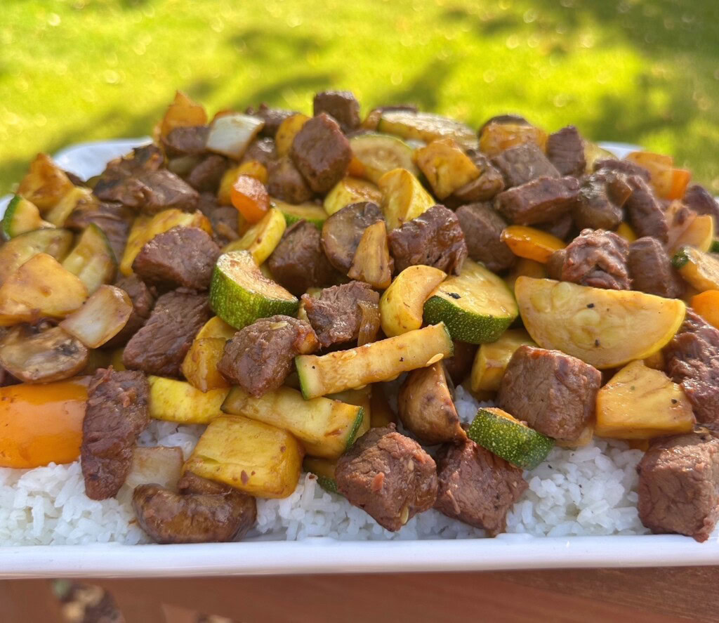 Close-up photo of teriyaki stir-fry on a bed of rice.