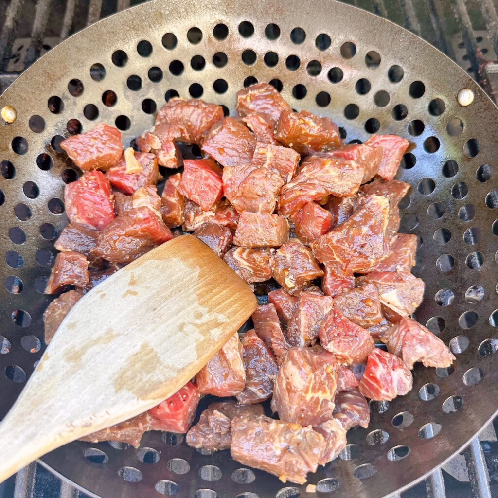 Grilling meat in a grilling basket on the BBQ.
