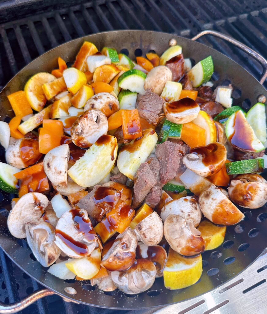 Adding a drizzle of teriyaki sauce to the vegetables.