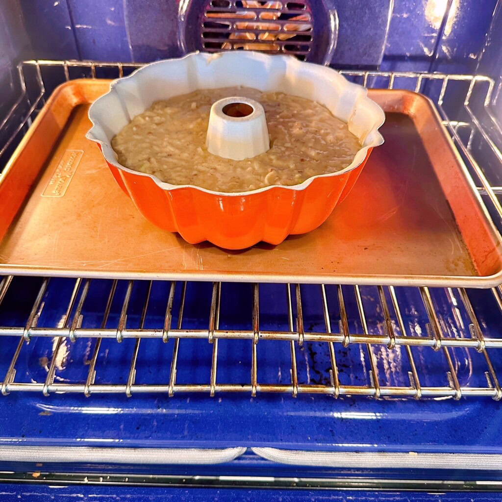 Placing apple bundt cake in the oven on the center rack.