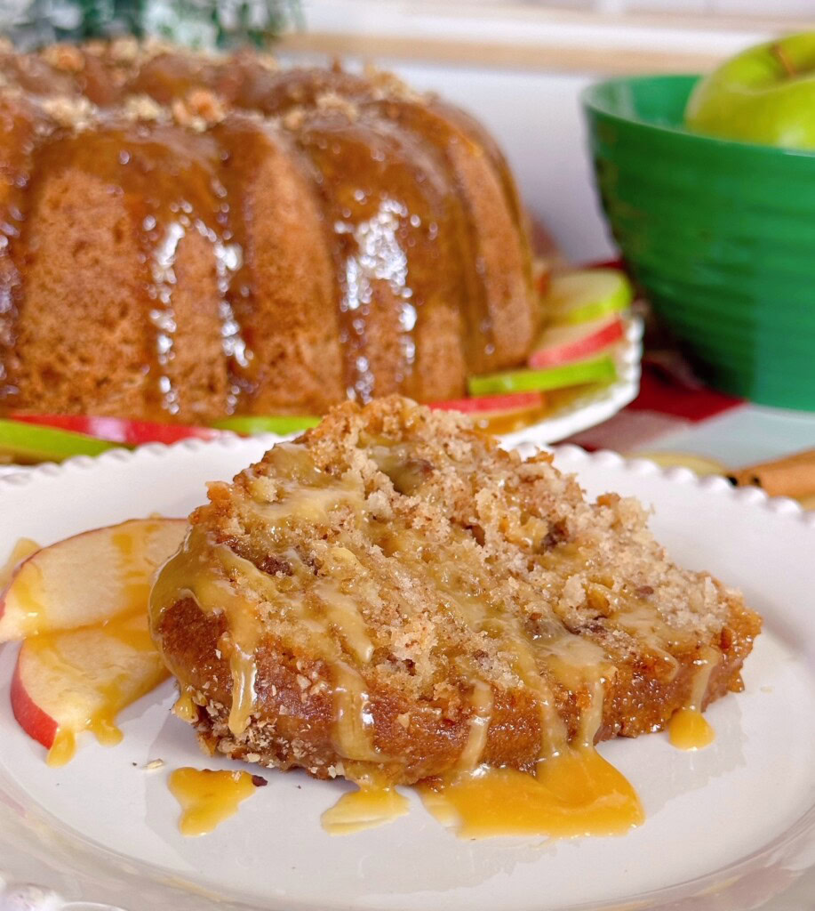 Fresh baked apple cake with a slice cut out on a dessert plate with caramel sauce.