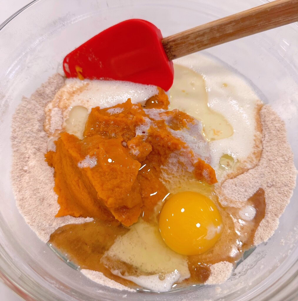 Adding "wet" ingredients to the dry ingredients for the pumpkin muffins.