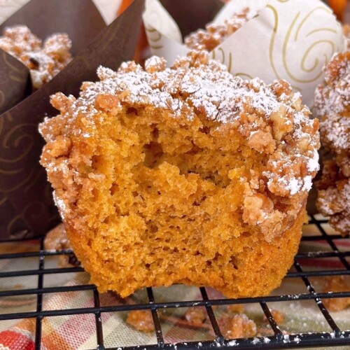 Up close photo of pumpkin muffin with streusel topping with a bite missing.