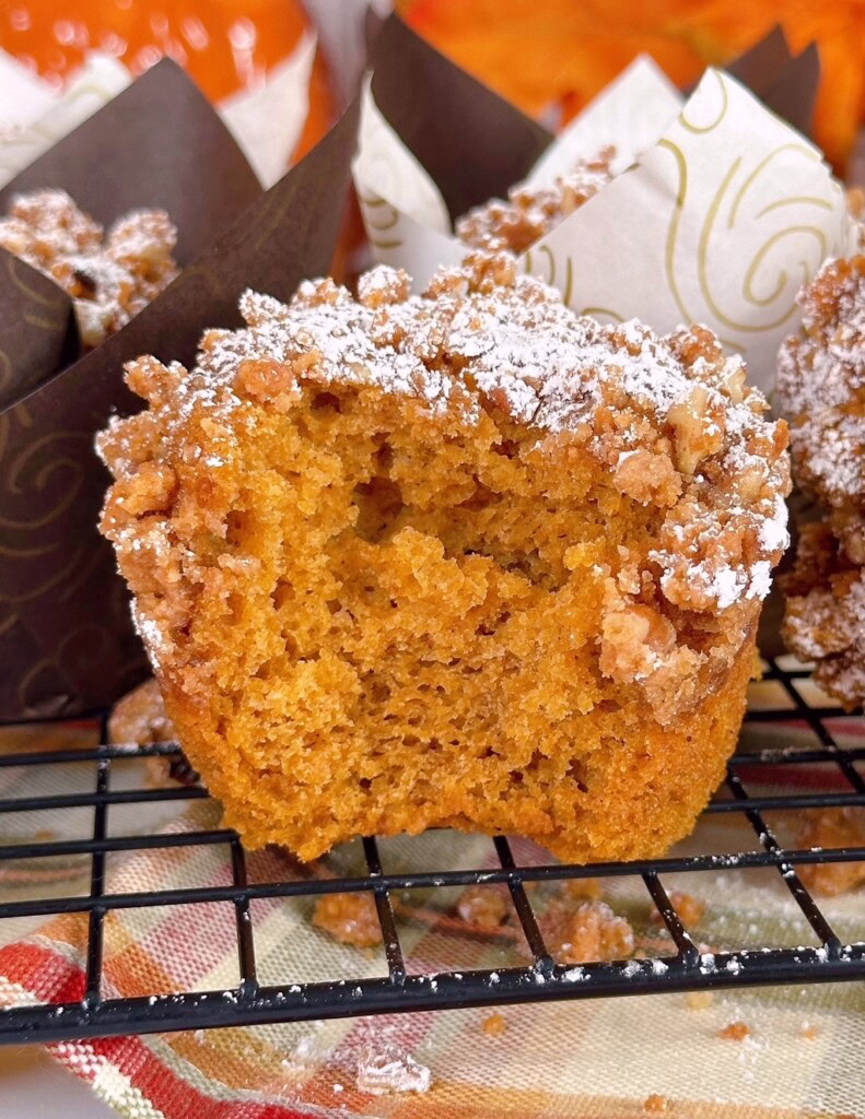 Up close photo of pumpkin muffin with streusel topping with a bite missing.