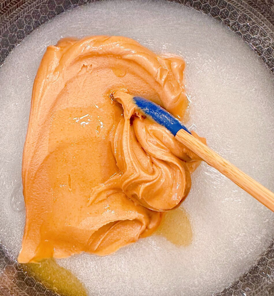 Adding peanut butter and vanilla to sugar mixture in sauce pan.
